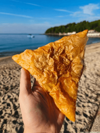 Hands stretching phyllo dough on a wooden table